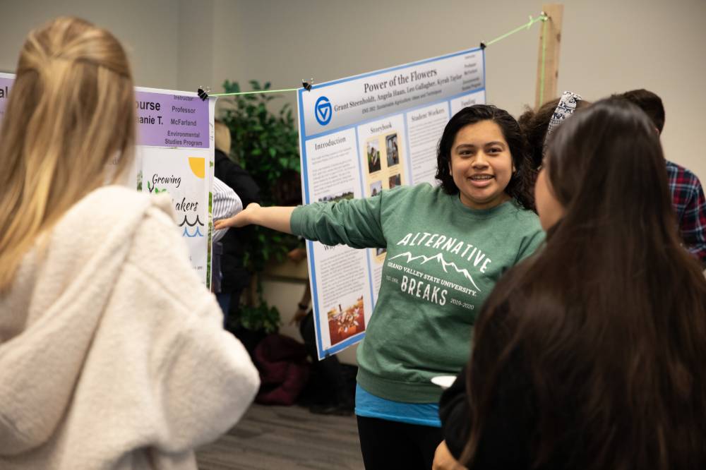 A student shares a poster presentation with two guests